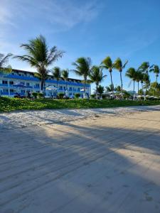 a beach with palm trees and a blue building at Marinas Tamandaré Flat in Tamandaré