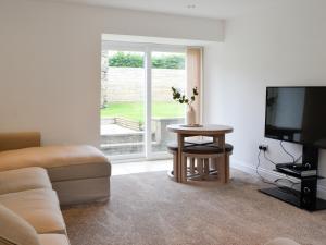 sala de estar con sofá, TV y mesa en Kirroughtree Steading 2 - Uk42904, en Newton Stewart