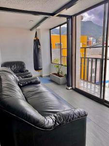 een leren bank in een woonkamer met een groot raam bij Apartamentos céntricos y cómodos en Chapinero in Bogota