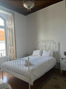 1 cama blanca en un dormitorio blanco con ventana en Casa da Rainha, en Azambuja