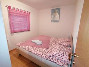 um pequeno quarto com uma cama e uma janela rosa em Apartmenthaus Viktoria em Šegotići