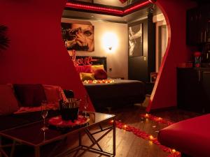 - un salon avec une chambre rouge dotée d'un lit et d'une table dans l'établissement Sensual Room Love Room Nancy Sauna Double Douche, à Nancy