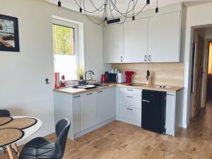 a kitchen with white cabinets and a table and chairs at Skoczybruzda Apartamenty in Chmielno