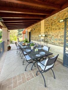 un patio con tavolo, sedie e parete in pietra di VILLA in 8 ettari di campagna, a 20' dal mare a Casa Piccirillo