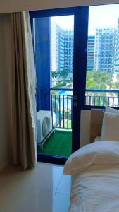 a room with a bed and a window with a balcony at Sea Residences - Classy Unit Near Mall of Asia, Arena, Ayala, Ikea, Okada, SMX, PITX, Airport in Manila