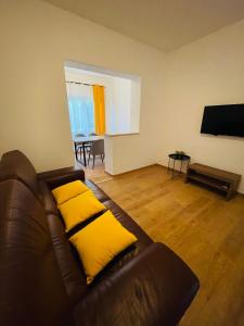 a living room with a leather couch with yellow pillows at Apartmani Roko&Lovre Paklenica in Starigrad