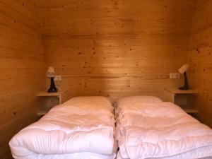 a bed in a wooden room with two lamps at Family Woodlodge High Chaparral in Oorsbeek
