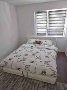 a white bedroom with a bed with a comforter at Apartments FOUR SEASONS in Sarajevo