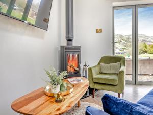 ein Wohnzimmer mit einem Kamin, einem Tisch und einem Stuhl in der Unterkunft The Stables in Littleborough