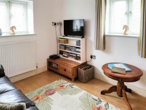 a living room with a table and a tv at Keepers Cottage in Docking