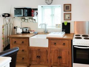 a kitchen with a sink and a stove at Keepers Cottage in Docking