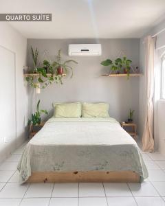 a bedroom with a bed with plants on the wall at Refúgio Urbano in Campina Grande
