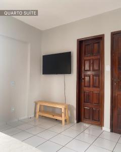 een kamer met een tv aan de muur en een houten tafel bij Refúgio Urbano in Campina Grande