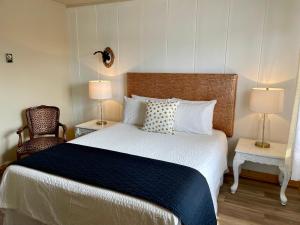 a bedroom with a large bed with two lamps and a chair at Hôtel-Motel Vagues Vertes in Perce