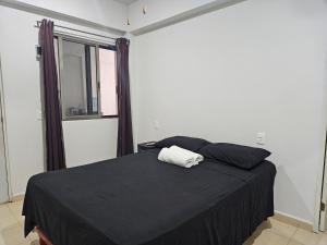 1 dormitorio con 1 cama con manta negra y ventana en Hostal El Padrino, en Akumal