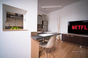 uma cozinha com uma mesa e cadeiras e uma televisão em Apartament Best Rest em Wadowice