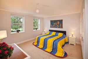 1 dormitorio con 1 cama amarilla y azul y 2 ventanas en River Views, Beccles - HOT TUB + Norfolk Broads, en Beccles