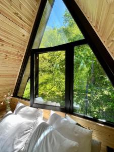 a bed in a room with a large window at GreenWood Cottages Merisi in Merisi +186 photos