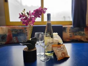 a bottle of wine and glasses on a table with flowers at Bungalow at Lake Lugano in Porlezza