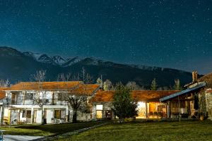 una casa di notte con montagne sullo sfondo di Къща за приятели Недкови a Vasil Levski