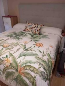 a bed with a blanket with flowers on it at Precioso apartamento recién reformado in Gijón