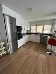 a kitchen with a stainless steel refrigerator and white cabinets at Precioso apartamento recién reformado in Gijón