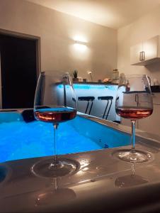 two wine glasses sitting on a counter with a swimming pool at Lavitas SPA in Moravče