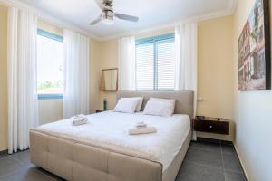 a bedroom with a large bed with two towels on it at Midrahov Luxury Apartment in Zikhron Ya‘aqov