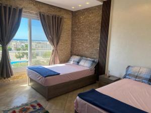 a bedroom with two beds and a large window at Amwaj amazing see view in Marsa Matruh