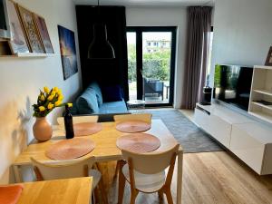 a living room with a wooden table and chairs at Apartament na Wydmie Gardenia Dziwnów in Dziwnów