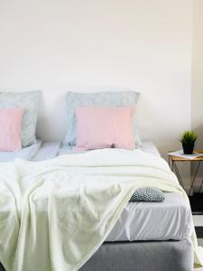 1 dormitorio con cama blanca y almohadas rosas en Scandinavian Apartment Hotel - Prison Museum 1- one room apartment, en Horsens