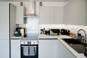 a kitchen with white cabinets and a stove top oven at Imagine That Property in Hemel Hempstead