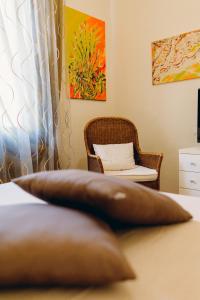 almohada marrón sentada en una cama con silla en Exclusive Aparthotel La Reunion, en Rávena