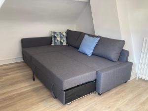a gray couch with two pillows on it in a room at F2 Le City Parking Netflix Wifi Gare in Évreux