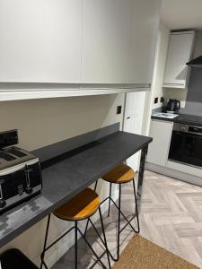 a kitchen with a counter and two stools in it at Chatsworth stables in Newbold