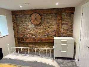Un dormitorio con una pared de ladrillo con un reloj. en Chatsworth stables en Newbold