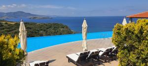 a pool with chairs and umbrellas and the ocean at Villa Molivos Castle in Mithymna