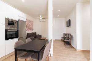 a dining room and living room with a black table and chairs at Apartamentos Cervantes 17 in Seville