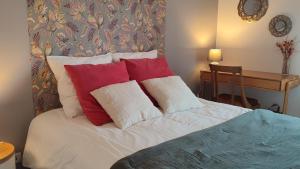 un lit avec des oreillers rouges et blancs et un bureau dans l'établissement Calme et verdure à Poissy 50 m2 parking terrasse, à Poissy 14 autres photos