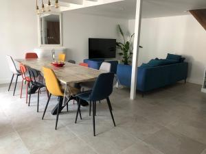 a dining room with a table and a blue couch at Maison Pécheur Golfe Morbihan Séné in Séné +8 photos