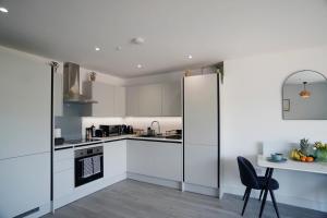 a kitchen with white cabinets and a table with a chair at Imagine That Property in Hemel Hempstead