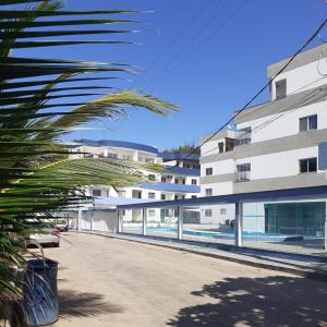 a building with a palm tree in front of it at Cobertura vista para o mar e piscina in Piúma