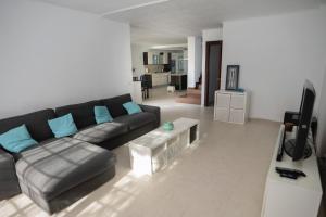 uma sala de estar com um sofá preto e uma televisão em Spacious Duplex with garden in Sotogrande em Sotogrande