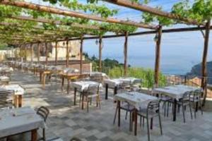 un gruppo di tavoli e sedie in un patio di NIDO TRA GLI ULIVI a Finale Ligure