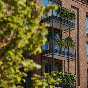 un edificio de ladrillo con balcones con plantas. en Green Estate Old Town Apartment, private parking, balcony, en Gdansk
