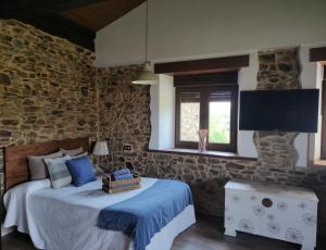 1 dormitorio con cama y pared de piedra en MINI PICONEIRO II, en Pravia