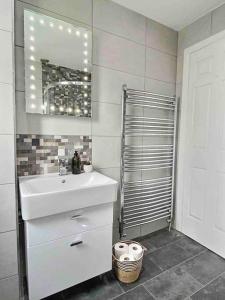 a bathroom with a white sink and a mirror at Home in Solihull - Near NEC, BHX & Solihull Town Centre in Birmingham