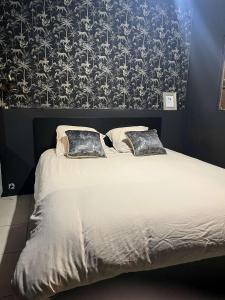 1 cama con 2 almohadas en un dormitorio con papel pintado en Love room chez Adan, en Arles