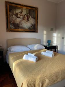 two towels on a bed with a painting on the wall at Hotel Villaggio Ristorante Pizzeria Museo TANIT in Carbonia