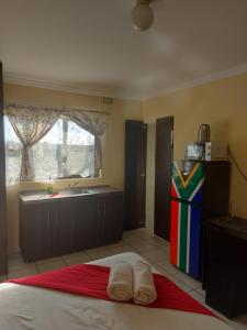 ein Schlafzimmer mit einem Bett und eine Küche mit einem Waschbecken in der Unterkunft Hlophe's Place in Hibberdene